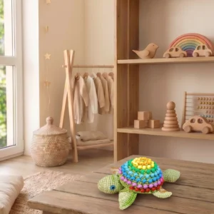 Horgolt fidget teknős szivárványos gyöngyös páncéllal egy fa asztalon gyerekjátékok között